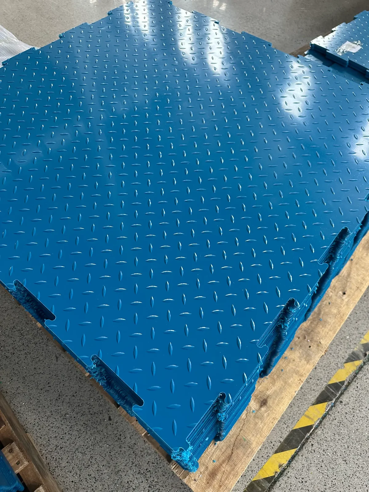 Company-supplied factory photo: close view of blue interlocking panel edges and surface pattern.